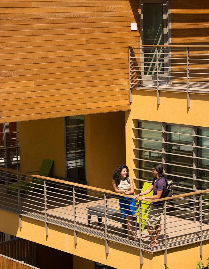 Two students talk on a balcony in west hall